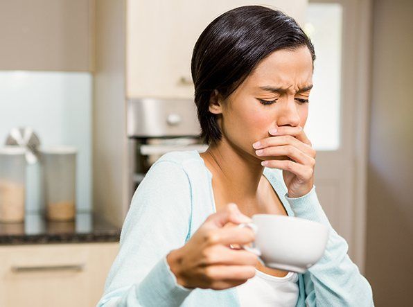 woman covering mouth while holding coffeecup