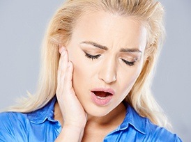 woman holding jaw in pain