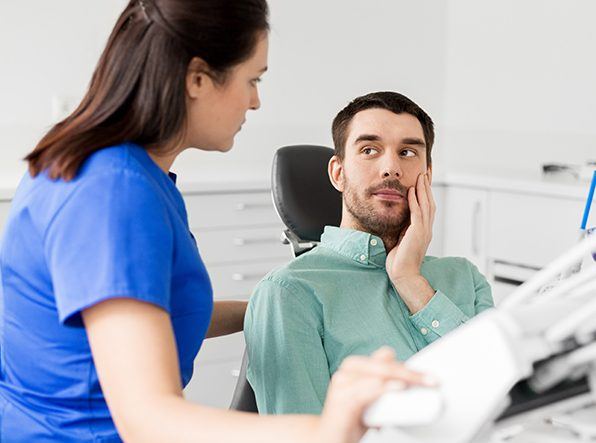 man holding cheek with dental emergency